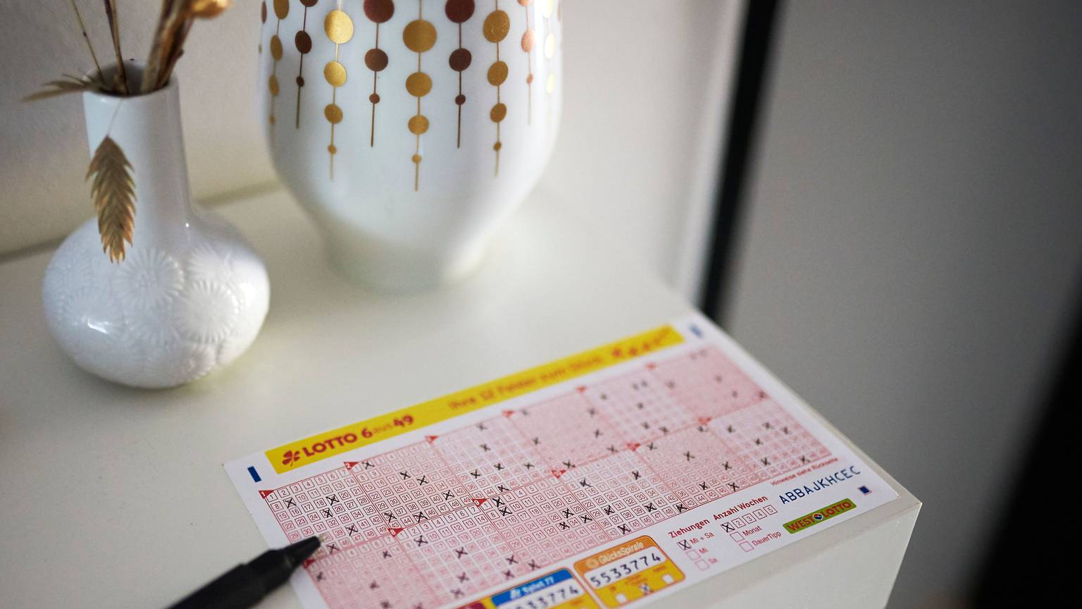 Ein LOTTO 6aus49 Schein liegt auf einem Tisch.