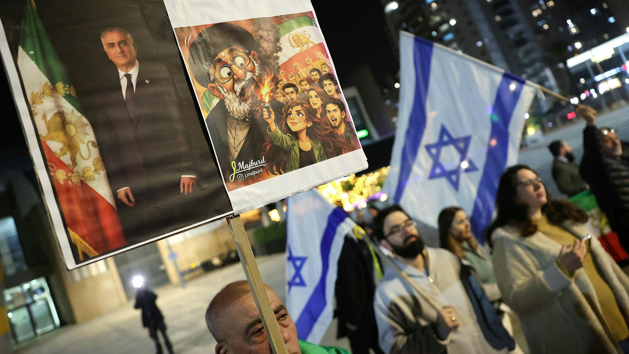 Menschen halten bei einer Demonstration in Solidarität mit den im Iran lebenden Protestierenden in der israelischen Zentralstadt Holon am 24. Januar 2026 ein Plakat mit dem Bild von Reza Pahlavi, dem Sohn des gestürzten Schahs von Iran, hoch.