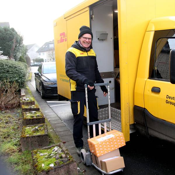 Ein Mann in DHL-Outfit mit einer Sackkarre.