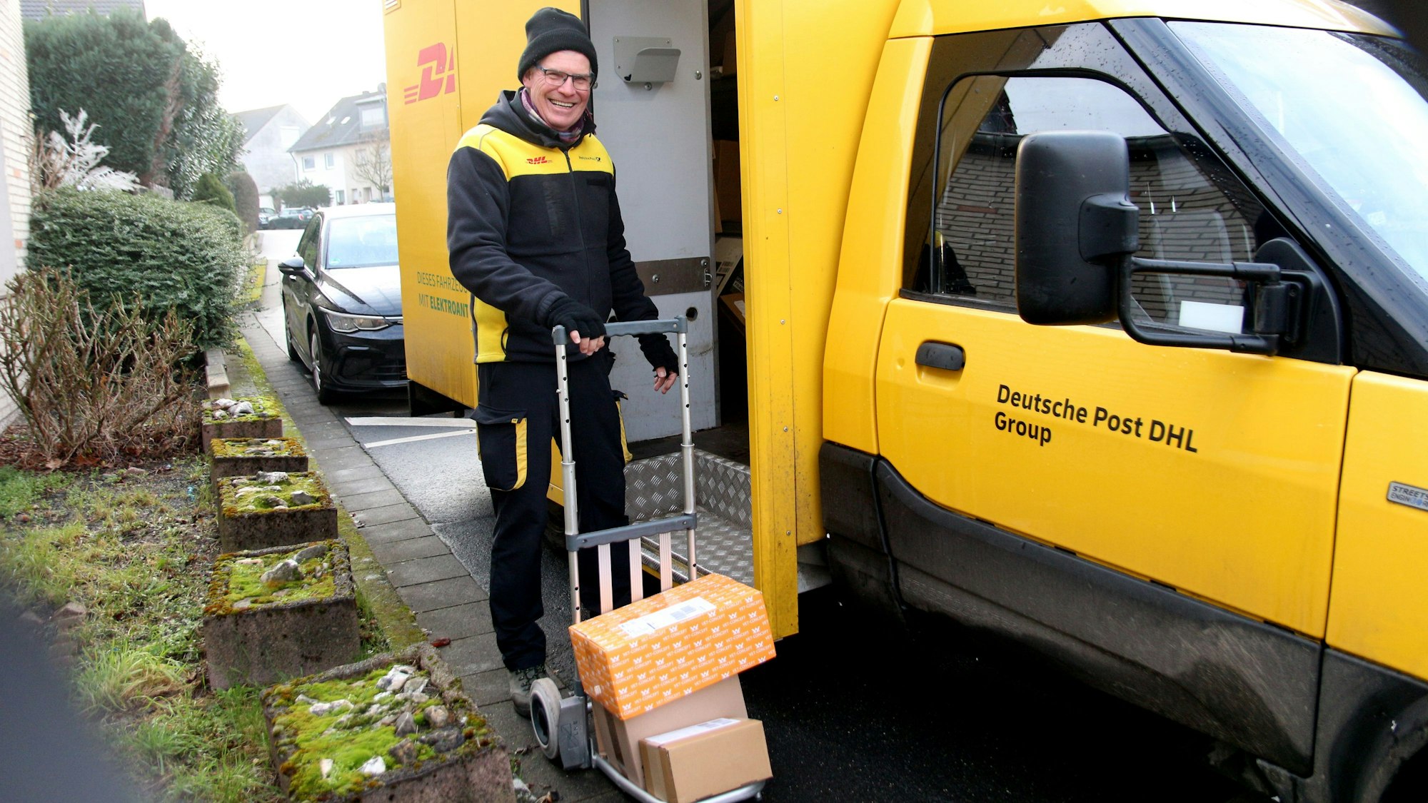 Ein Mann in DHL-Outfit mit einer Sackkarre.