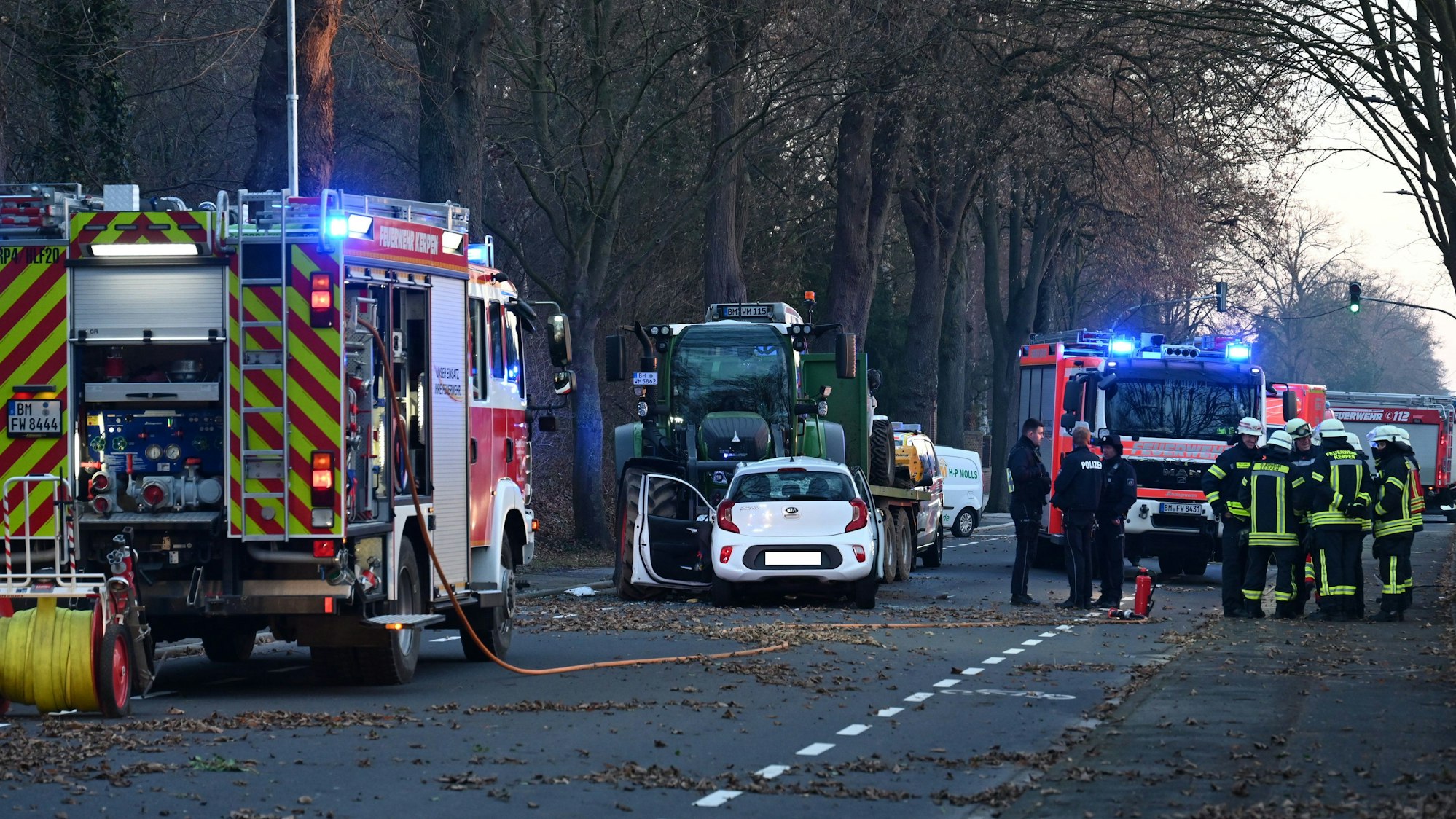 Nach dem Zusammenprall eines Kleinwagens und eines Traktors auf einer Straße sind Feuerwehr und Rettungsdienst im Einsatz.