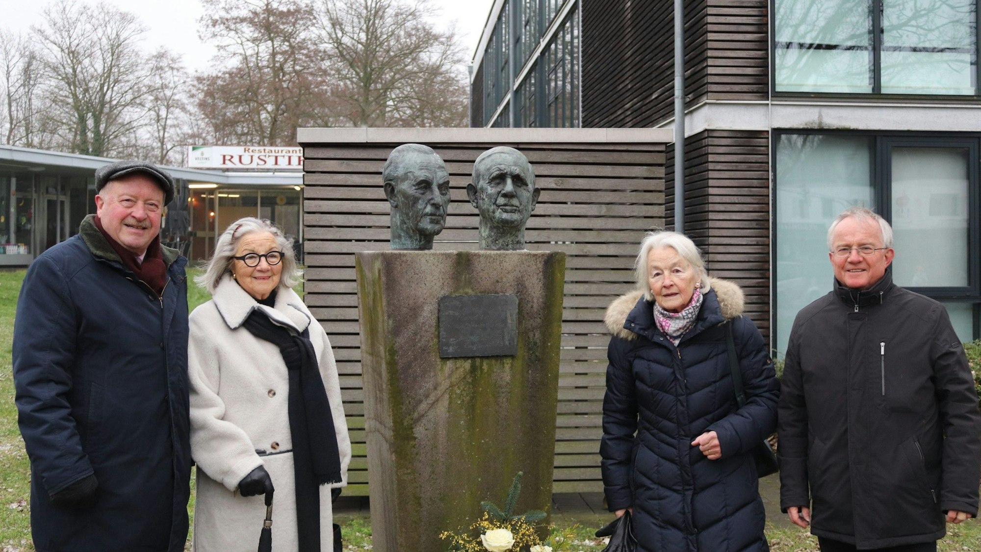 Vier Menschen stehen neben einer Büste.