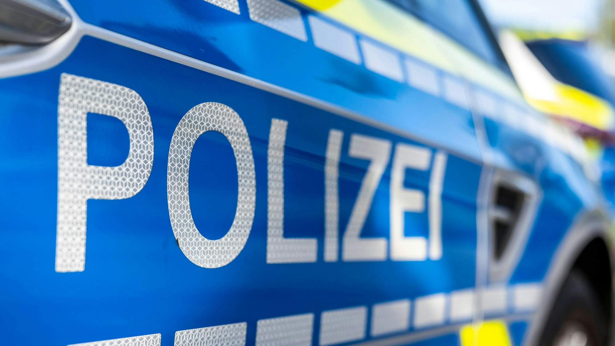 An der Tür von einem Streifenwagen steht der Schriftzug „Polizei“.