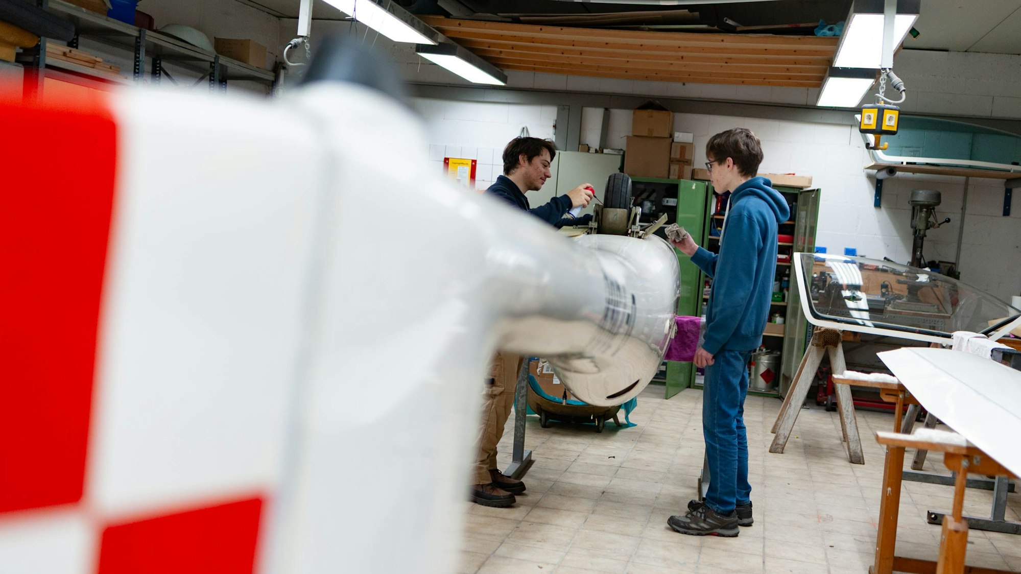 Zu sehen sind zwei Jugendliche am Flugzeug, das Rad nach oben.