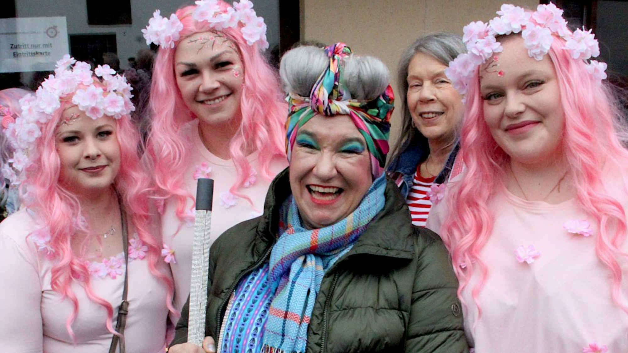 Drei mir rosafarbenen Perücken verkleidete Karnevalistinnen stehen mit Comedienne Achnes Kasulke zusammen.