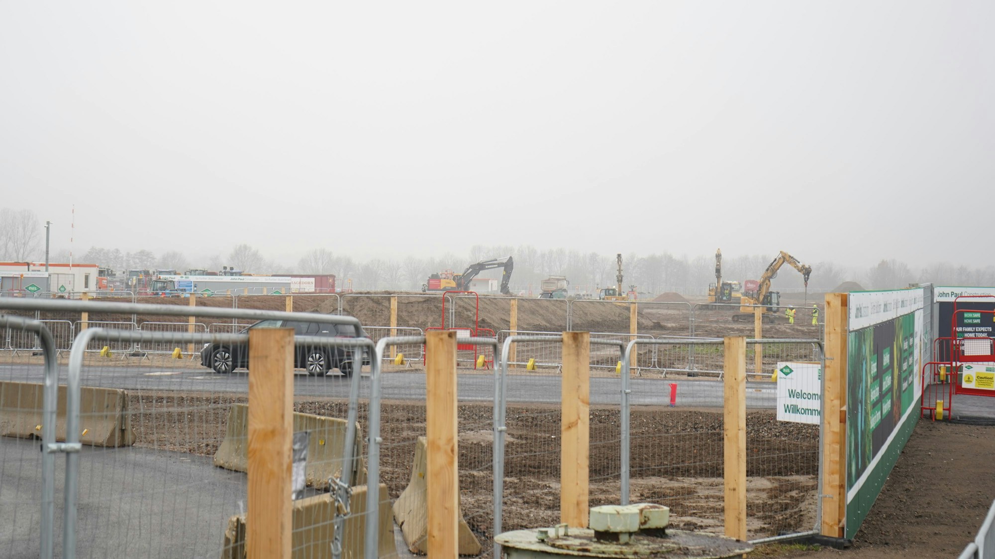 Mehrere Bagger sind hinter einem Bauzaun im Einsatz.