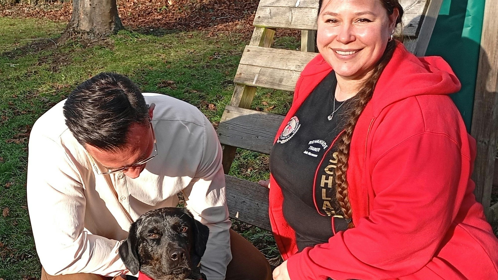 Das Foto zeigt zwei Menschen mit einem Hund.