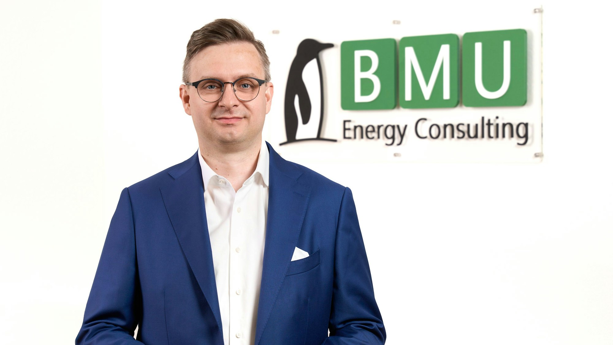 Ein junger Mann mit Brille und blauem Jacket.