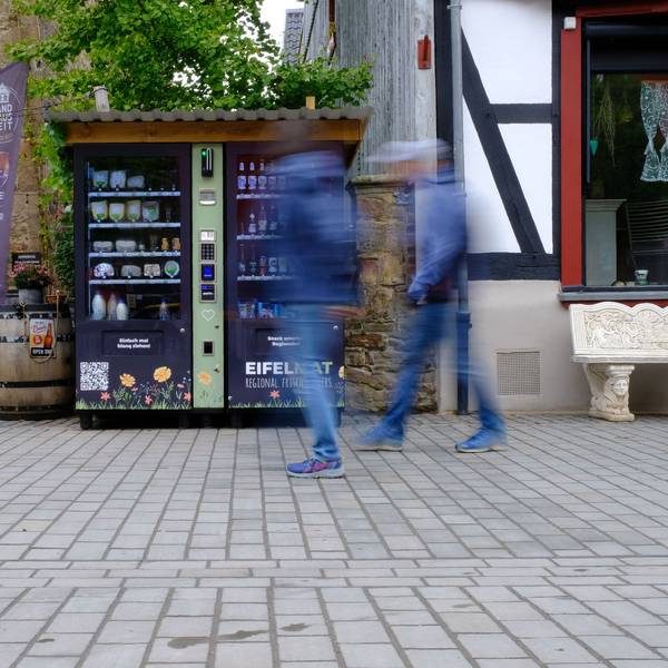 Zwei Männer gehen an zwei Verkaufsautomaten vorbei. Beide Männer sind bewegungsunscharf.