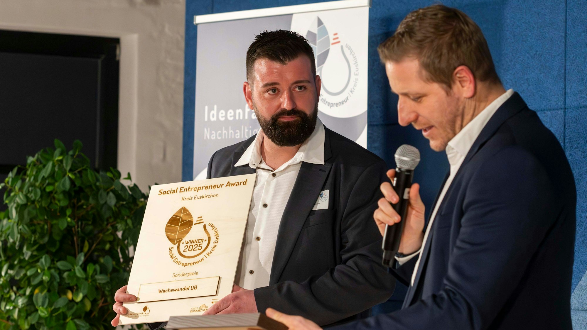 Das Bild zeigt den Gründer von Wachswandel auf der Bühne mit Markus Ramers.