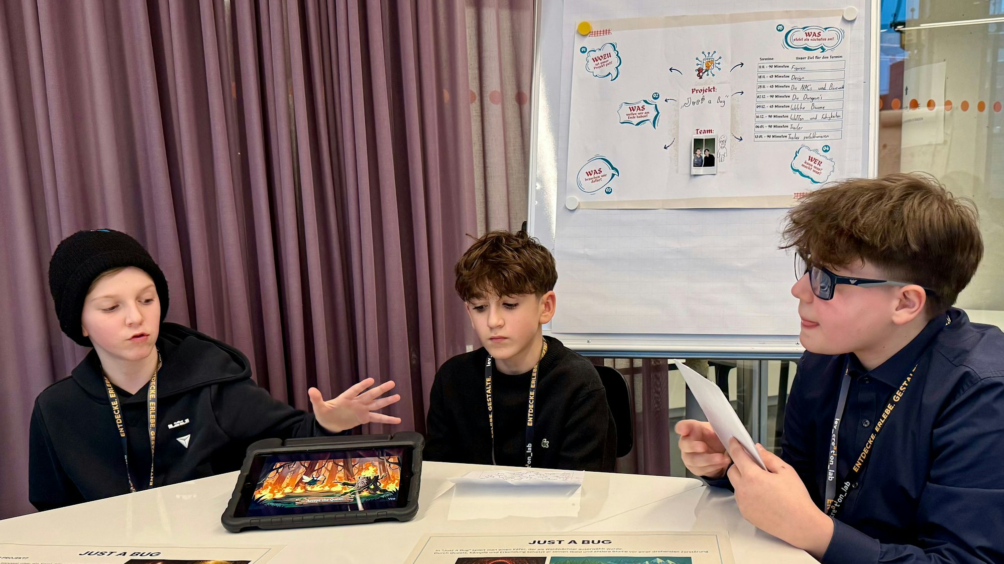 Drei Kinder, die ein Spiel mit Hilfe von Künstlicher Intelligenz entwickelt haben, sitzen an einem Tisch.