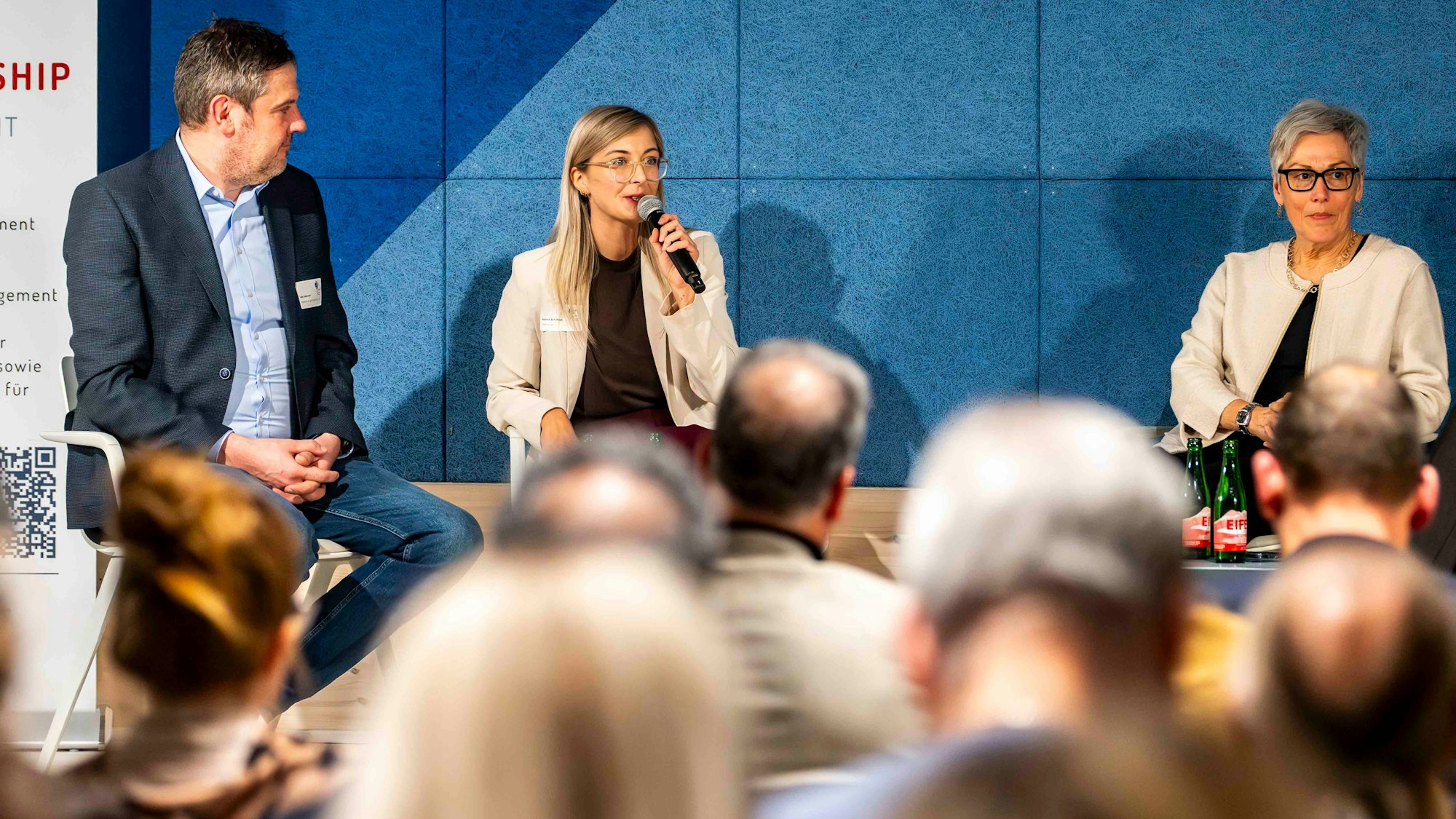 Das Bild zeigt einen Moment der Preisverleihung. Auf einer Bühne wird diskutiert.