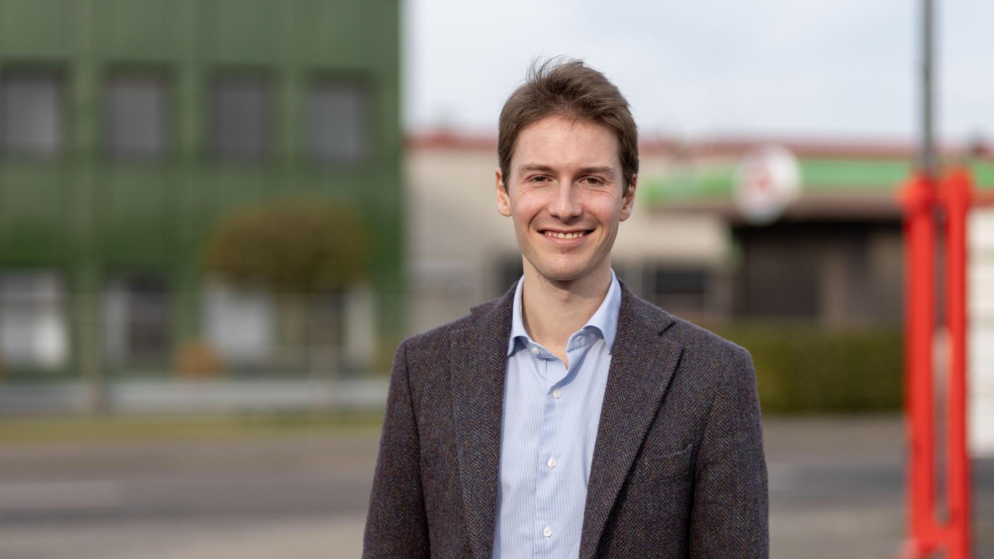 Ein junger Mann lächelt in die Kamera.