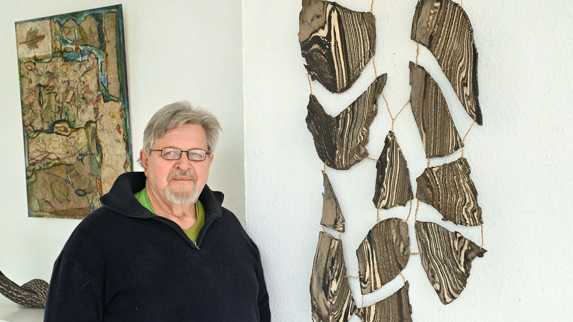 Rüdiger Westphal steht neben einem Bild und einer Keramik der Künstlerin Claudia Clement.