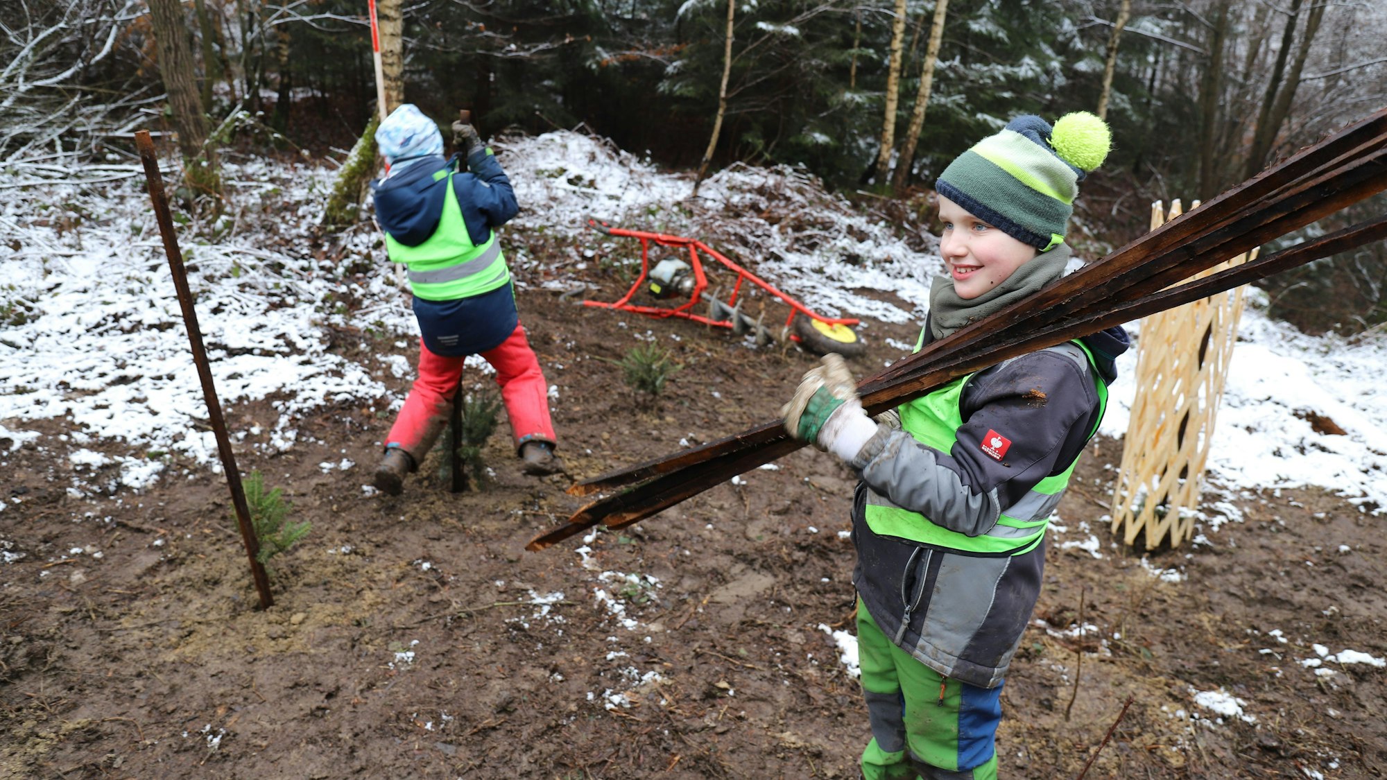 Lukas schleppt Robinien-Latten herbei, die in den Boden gerammt werden.