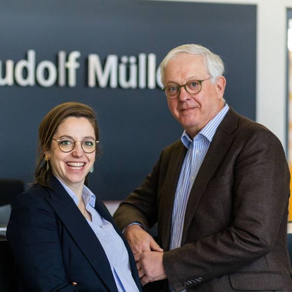 Eine jüngere Frau und ein älterer Mann lächeln in die Kamera.