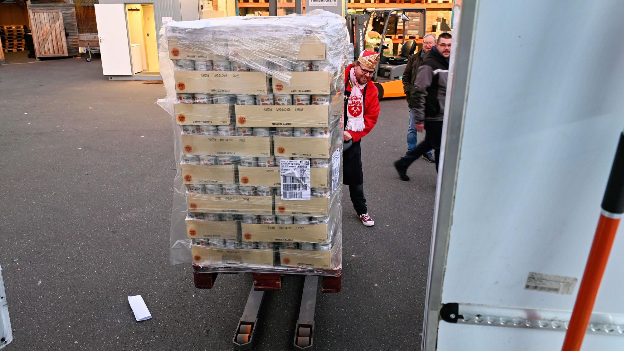 Torsten Krieg lädt als karnevalistischer Prinz verkleidet Lebensmittelkonserven auf ein Transportmittel.