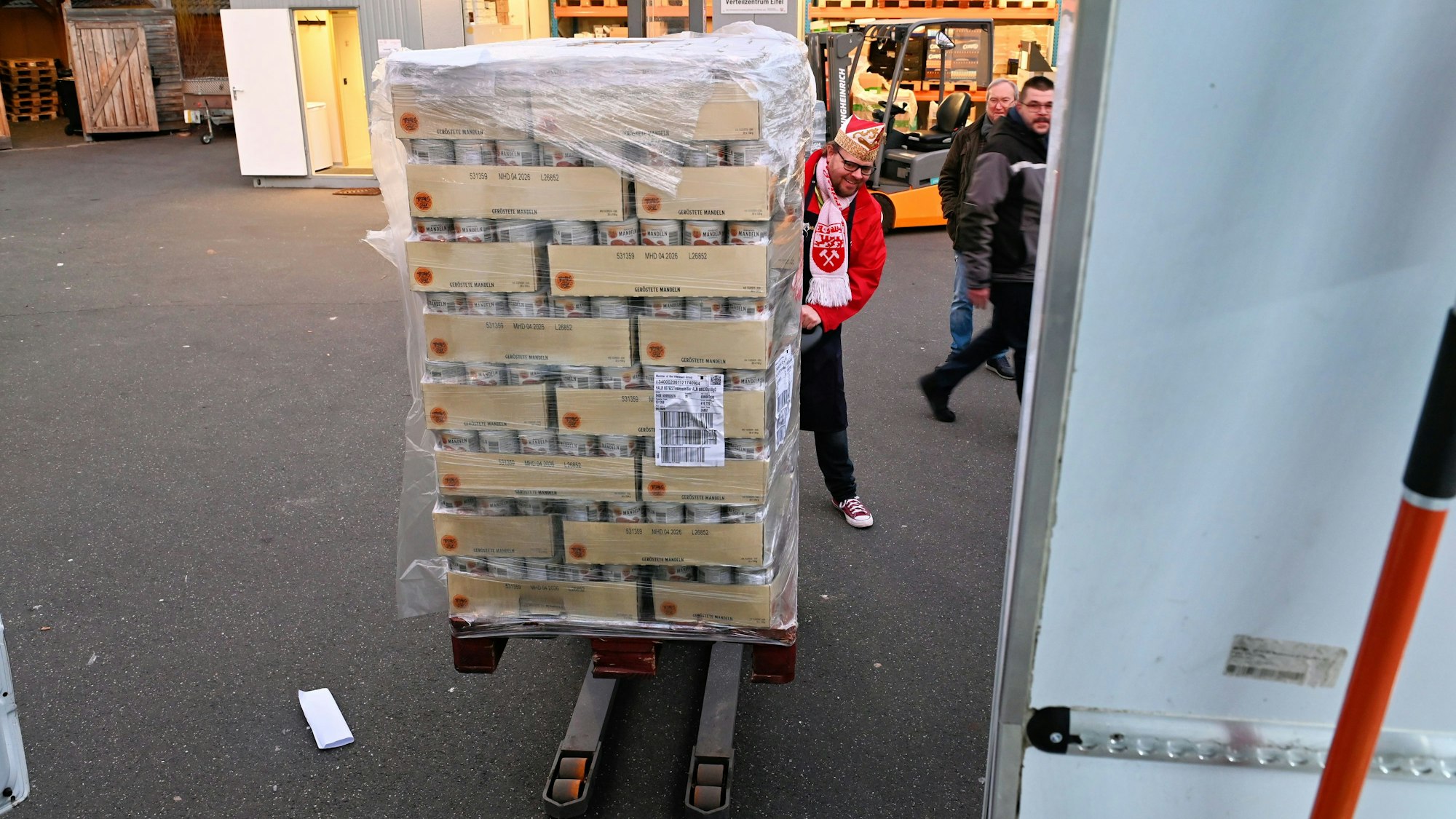 Torsten Krieg lädt als karnevalistischer Prinz verkleidet Lebensmittelkonserven auf ein Transportmittel.
