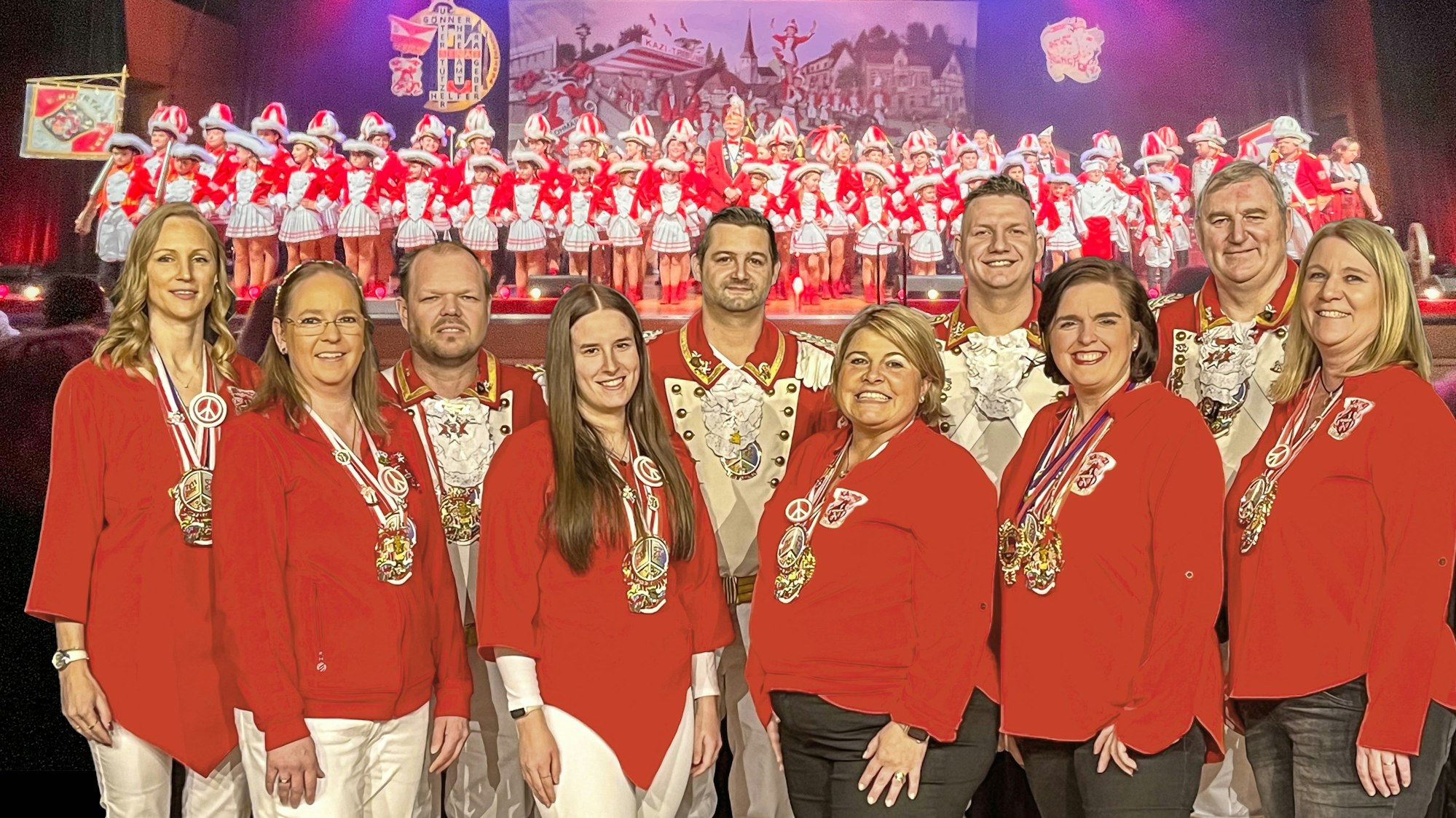 Im Hintergrund sieht man den Verein auf der Prunksitzung des KAZI mit allen aktiven Tänzern und Tänzerinnen sowie Elferrat, Senatoren und Vorstand. Davor steht die Arbeitsgruppe/Betreuer/Innen, die sich mit dem Thema Schutzkonzept verstärkt auseinandersetzen. 2.v.r.: Daniela Kuhn, Schutzbeauftragte, 3.v.r. Kristina Wingenfeld, die das Schutzkonzept mit verfasst hat.
