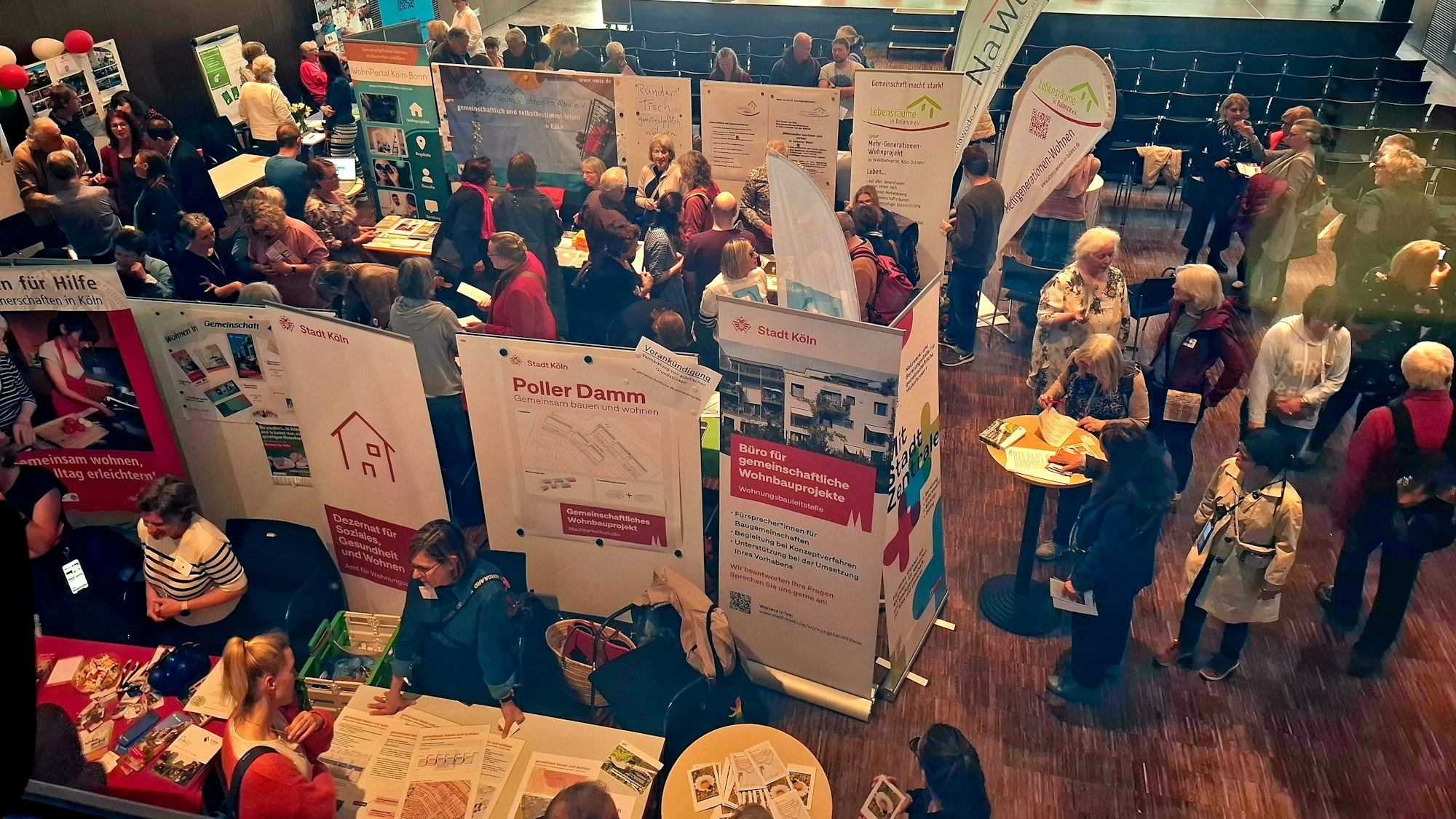 Blick auf verschiedene Stände, an denen Menschen anderen Menschen etwas über ihre Wohnprojekte.