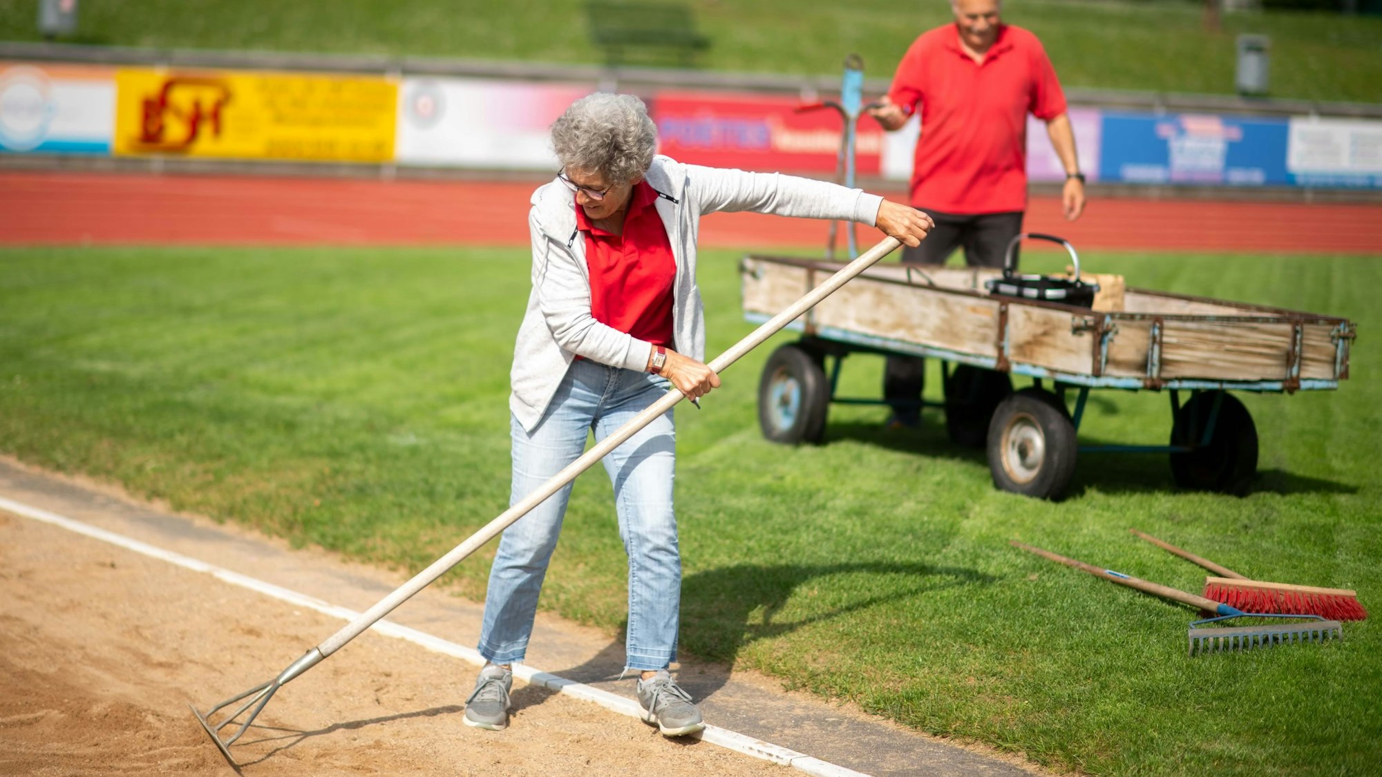 Bei einem Leichtathletik-Wettkampf helfen ein Mann (im Hintergrund) und eine Frau bei der Organisation.