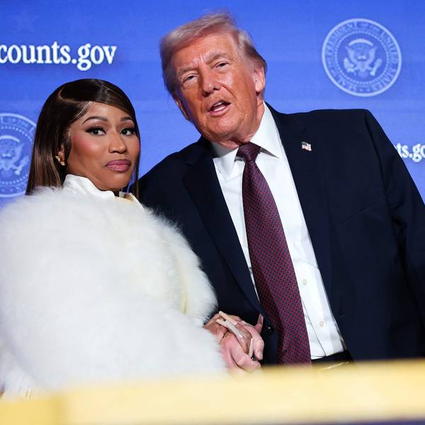 Die Musikerin Nicki Minaj (links, in weißem Kunstpelz) begleitet US-Präsident Donald Trump auf die Bühne, während er am 28. Januar 2026 im Andrew W. Mellon Auditorium in Washington, D.C., eine Rede auf dem Trump Accounts Summit des Finanzministeriums hält.