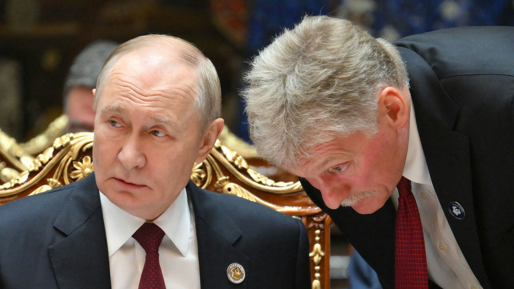 Russlands Präsident Wladimir Putin (l.) spricht mit Kremlsprecher Dmitri Peskow. (Archivbild)