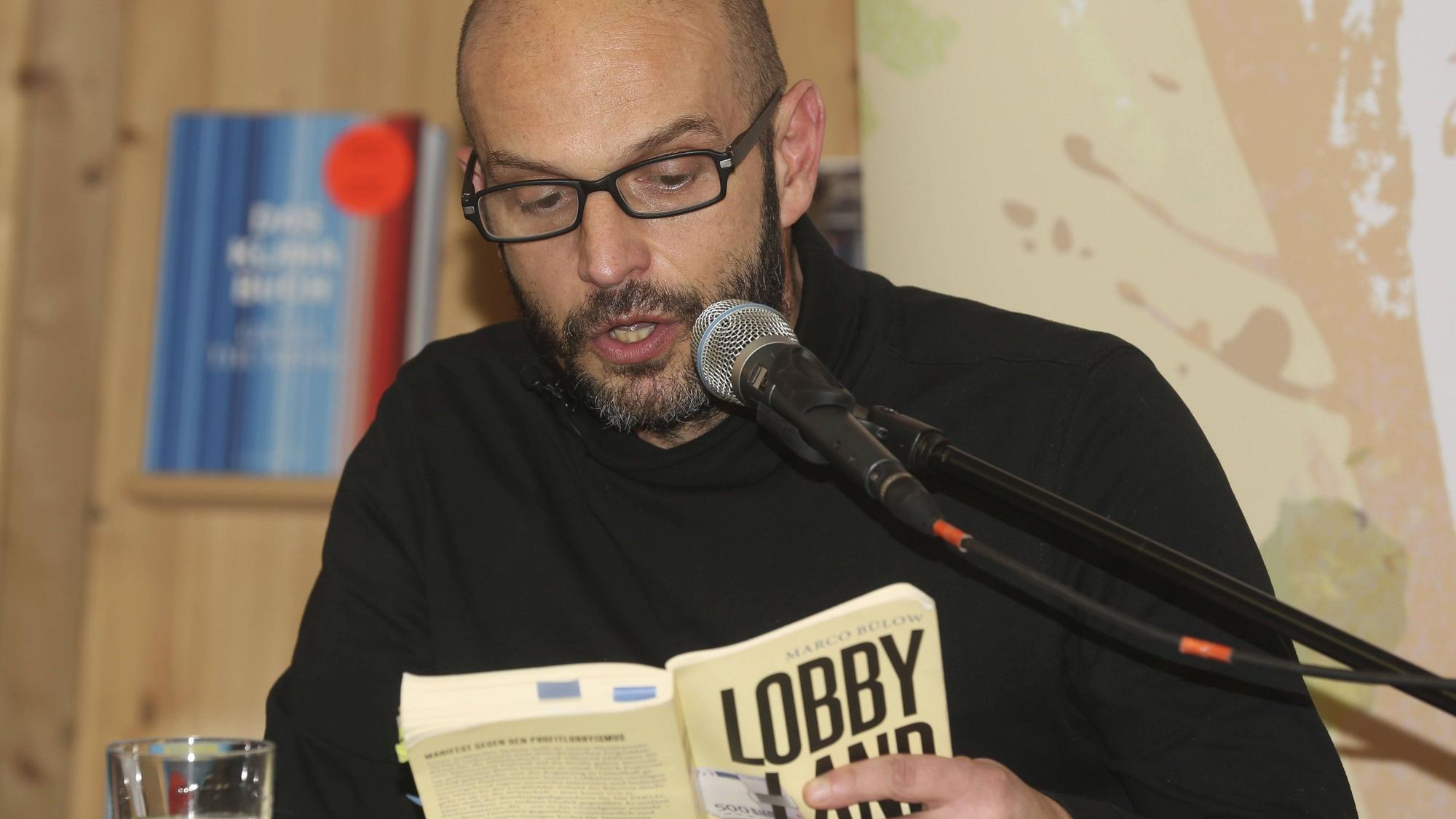 Marco Bülow liest aus einem Buch ins Mikrofon