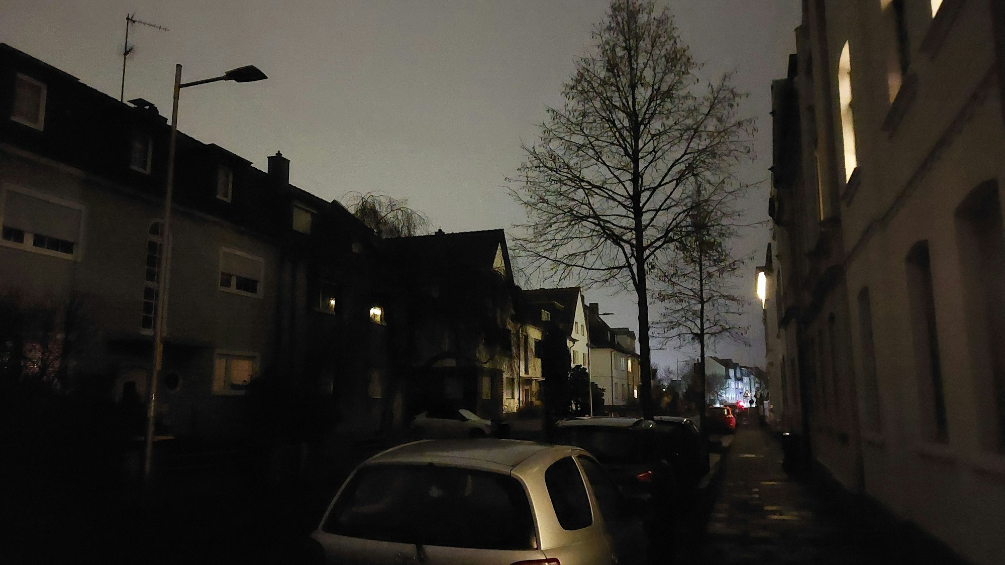 Eine dunkle Straße in einem Wohnviertel. Die Laternen sind nicht im Betrieb.