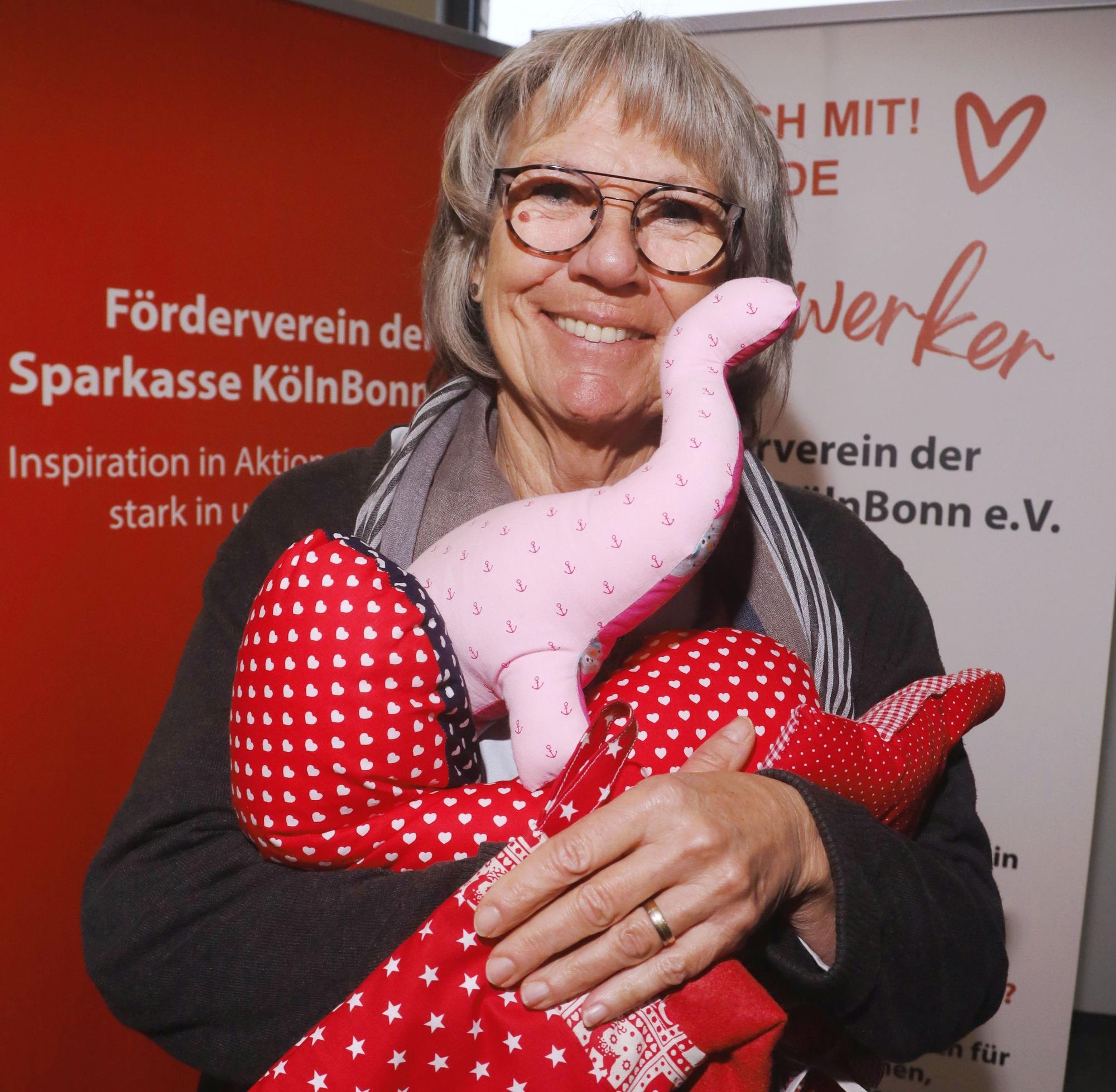 Das Bild zeigt Heike Dueren, die von den „Herzwerkern“ genähte Kissen präsentiert.
