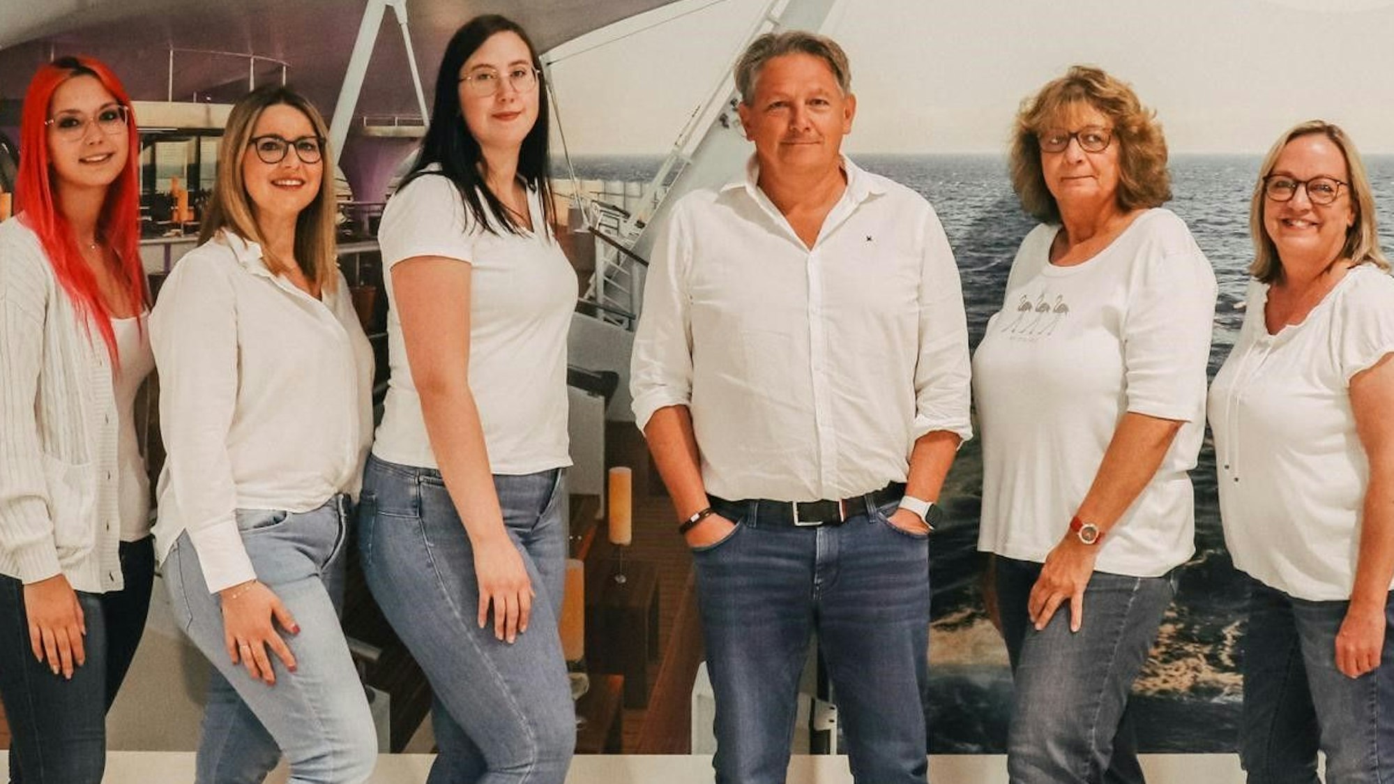 Das Bild zeigt das Team aus dem Reisebüro. Es hat sich zu einem Gruppenbild aufgestellt.