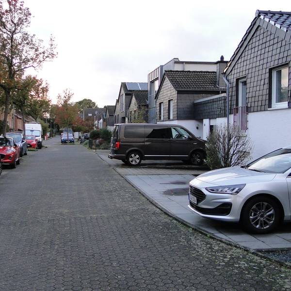 An einer Anwohnerstraße parken vor den einzelnen Grundstücken Autos.