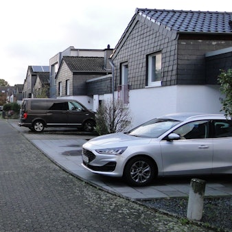 An einer Anwohnerstraße parken vor den einzelnen Grundstücken Autos.