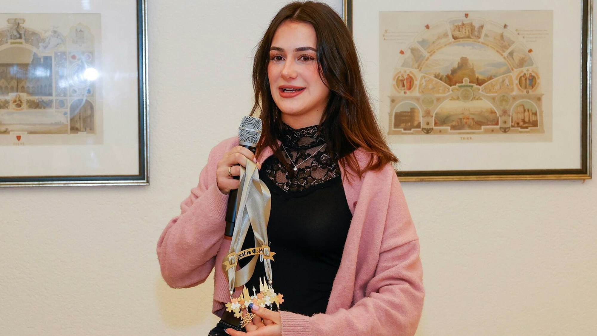 Hannah Homberg hält ein Mikrofon und ihren Orden in der Hand.