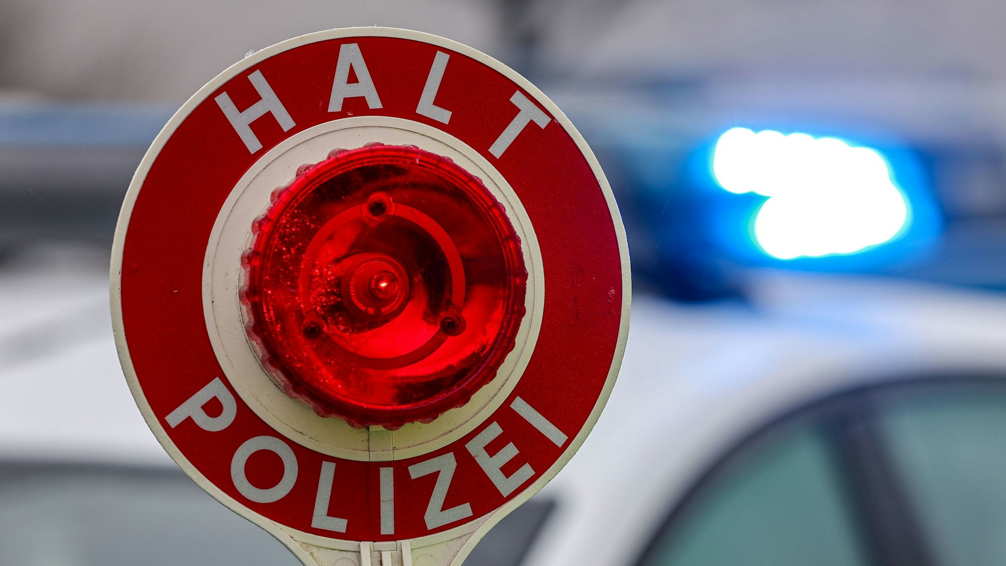 Ein Polizist hält eine Polizeikelle für eine Kontrolle.
