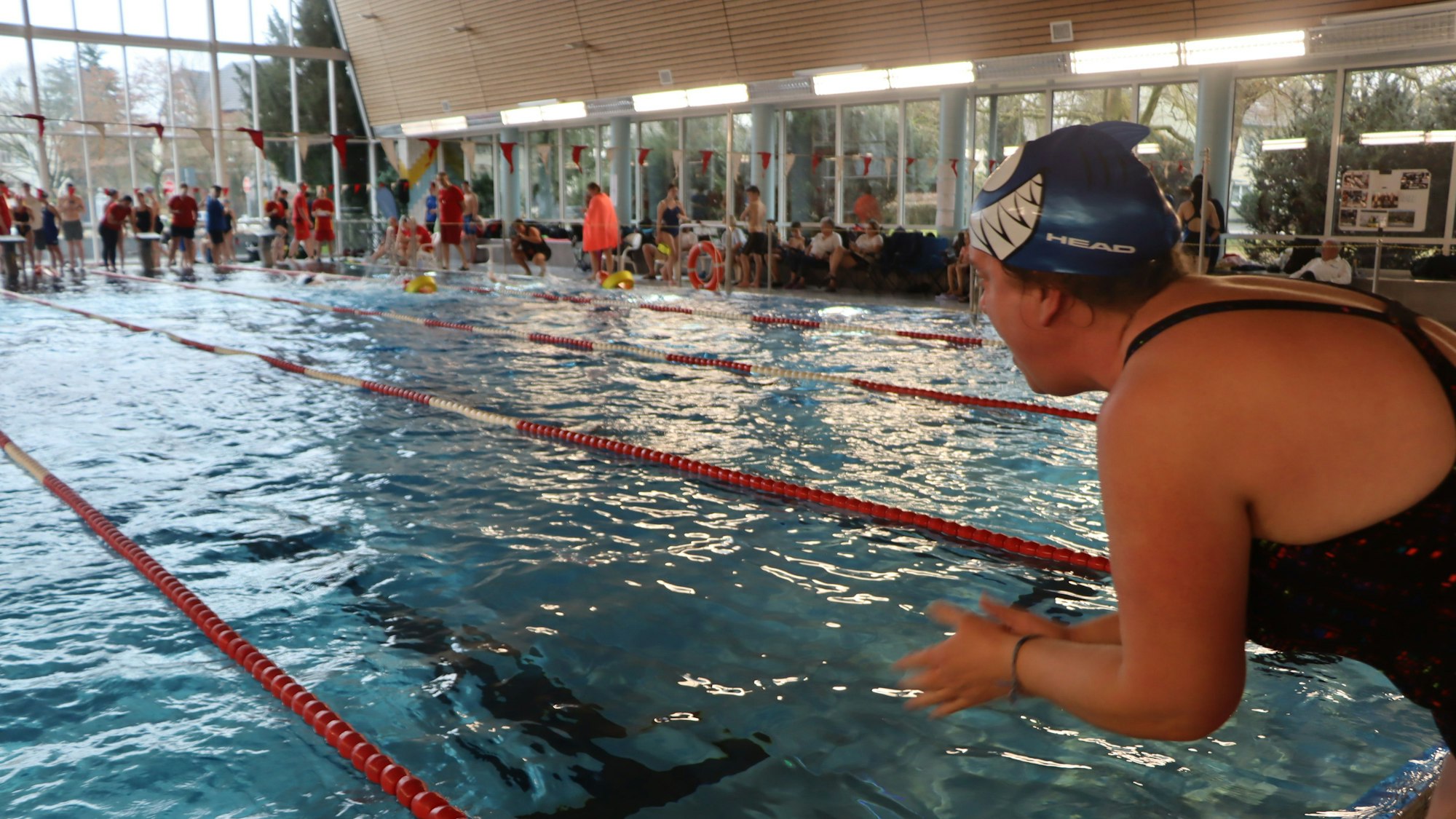 Zu sehen ist eine Schwimmerin vor dem Sprung vom Startblock ins Becken.