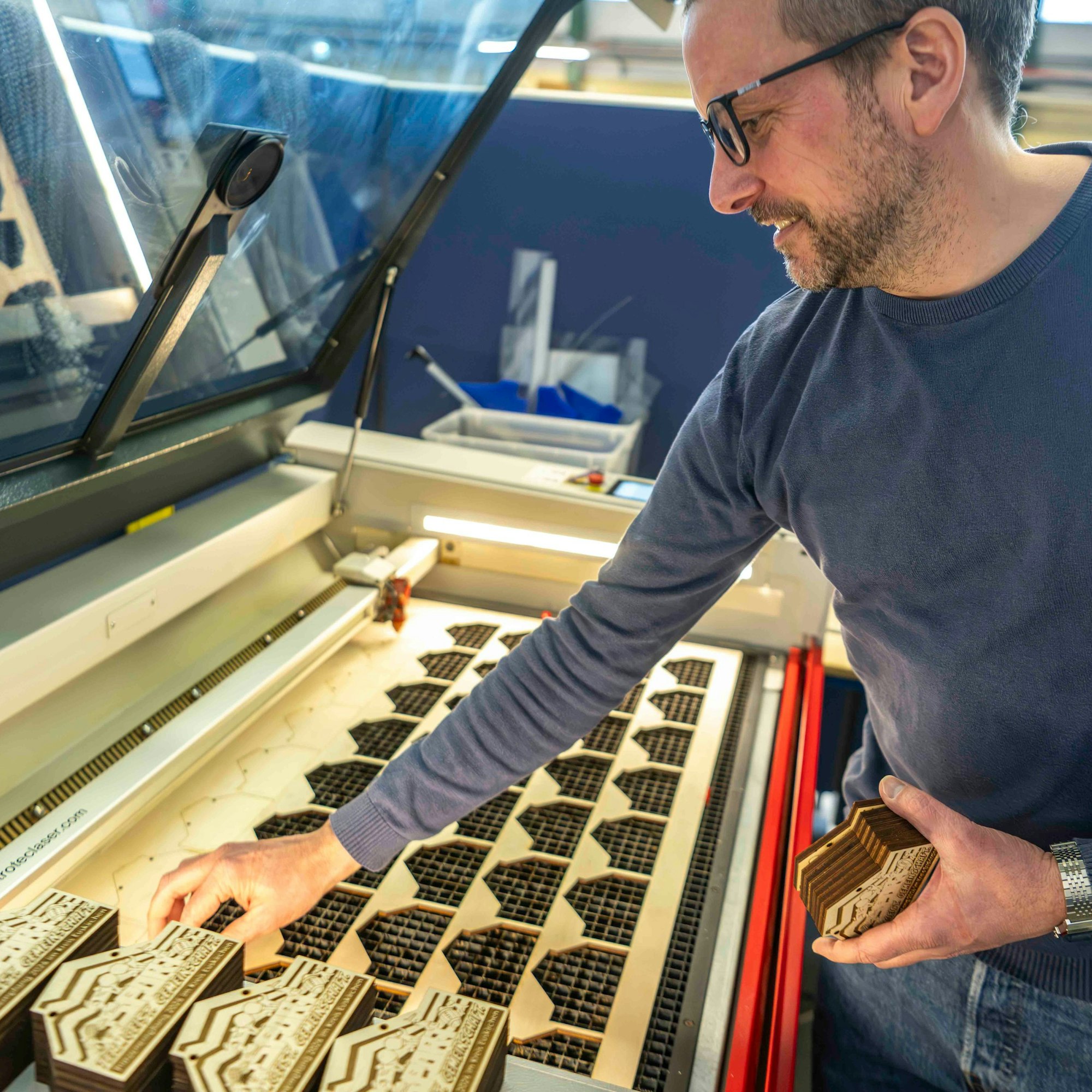 Der Betriebsleiter positioniert die hölzernen Orden in die Schablone der Maschine mit dem Laser.