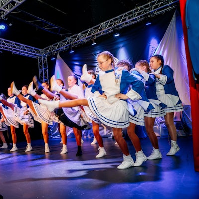 Eine Kindertanzgruppe tanzt auf einer Bühne.