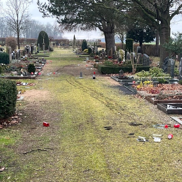 Auf einem Friedhofsweg liegen Grablichter, Glasscherben und anderer zerstörter Grabschmuck.