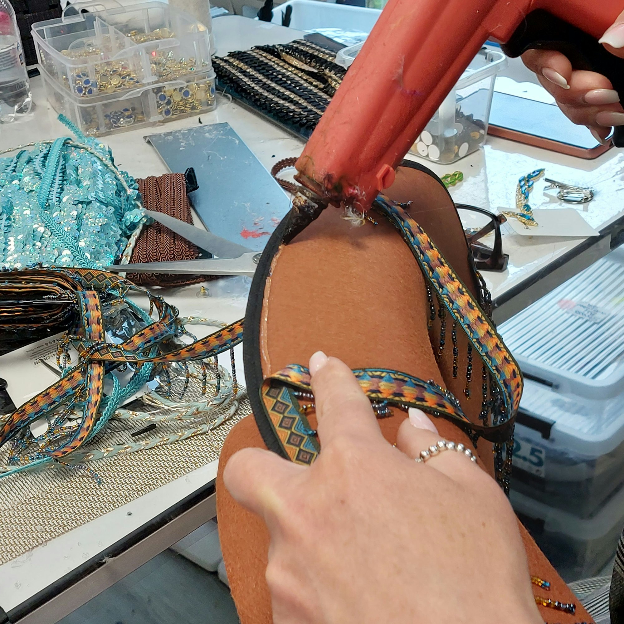 Eine Frauenhand arbeitet mit einer Heißklebepistole.