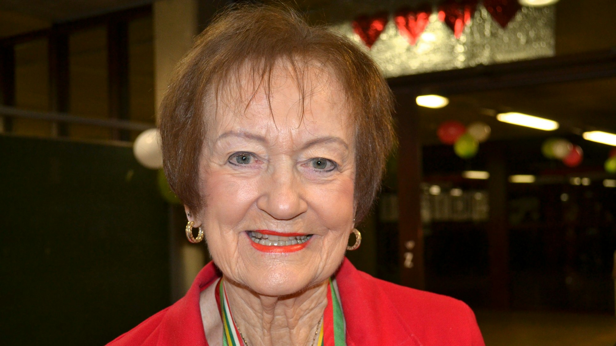 Eine ältere Frau in einer roten Jacke.