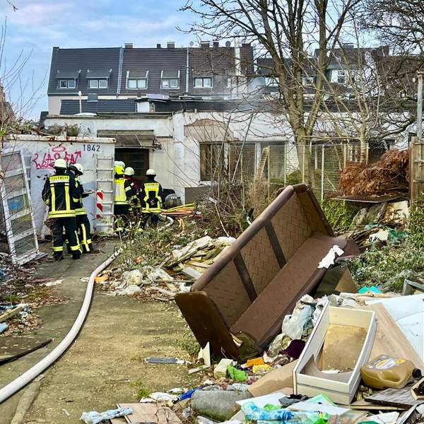 Feuerwehrleute in einem Hof an der Peschstraße in Wiesdorf