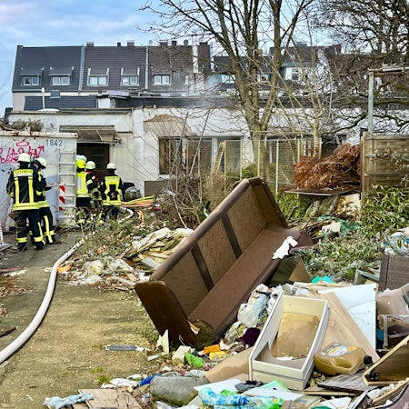 Feuerwehrleute in einem Hof an der Peschstraße in Wiesdorf