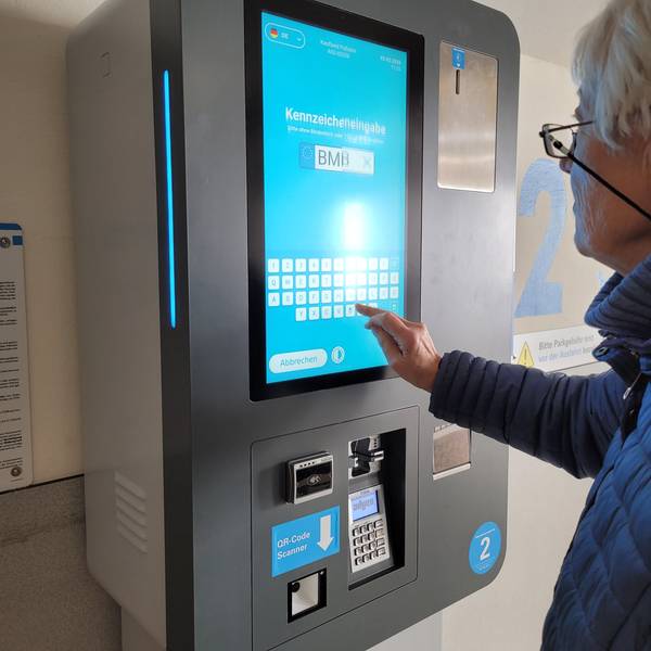 Ein Parkautomat, zu sehen sind ein Buchstabenfeld und ein Hand.