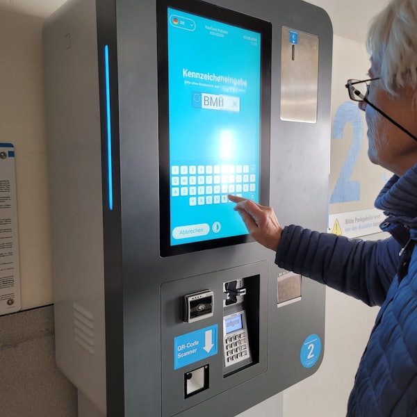 Ein Parkautomat, zu sehen sind ein Buchstabenfeld und ein Hand.