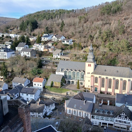 Das Bild zeigt die von Häusern umgebene Kirche und im Hintergrund Wald.