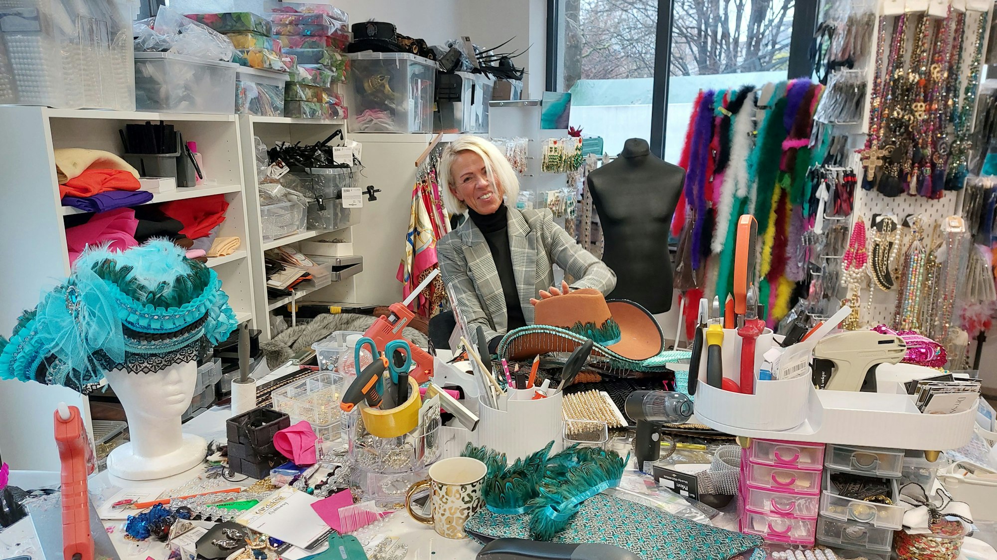 Eine Frau an einem Nähtisch mit bunten Stoffen und anderem Nähmaterial.