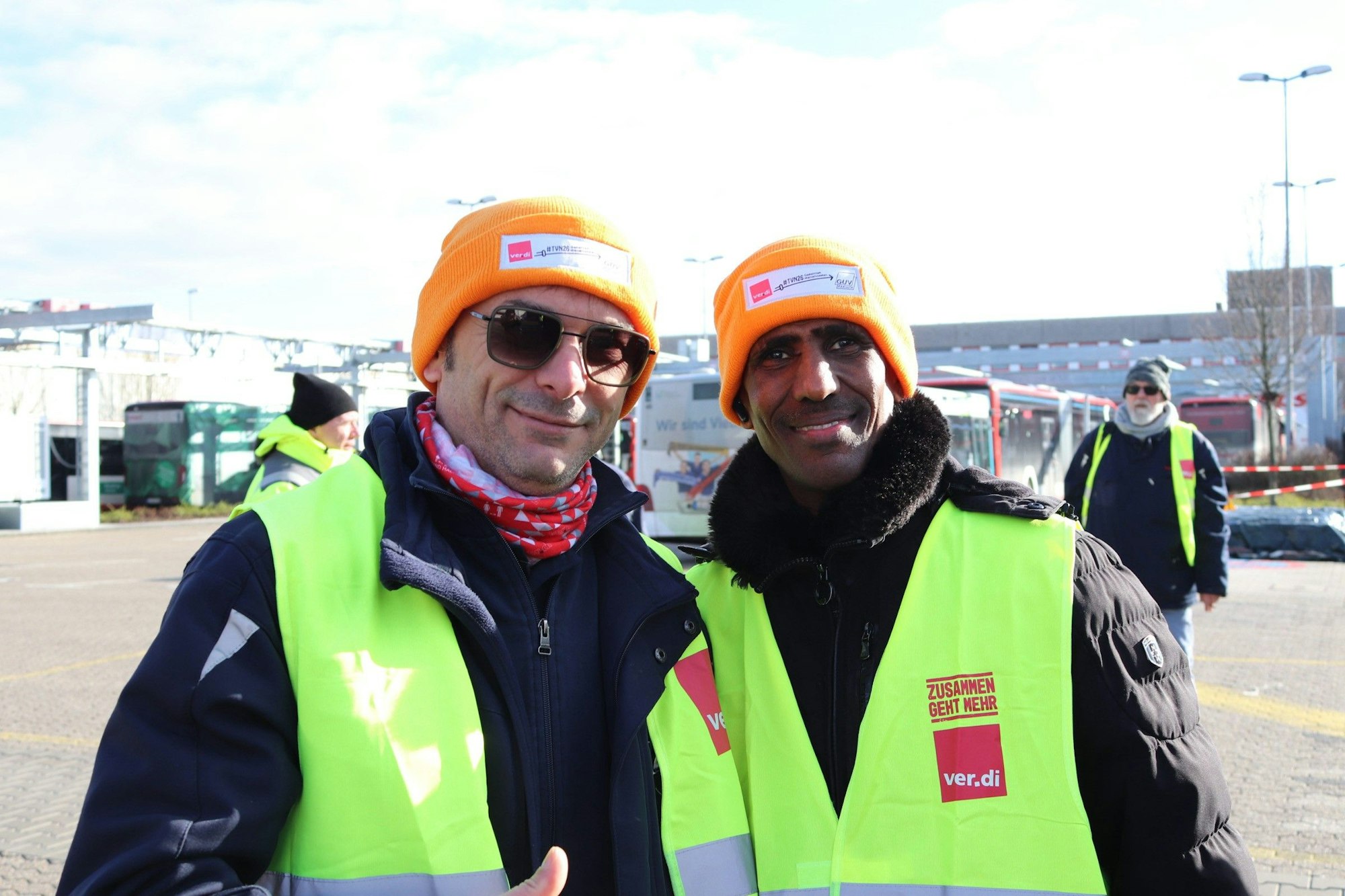 Zwei Menschen mit Warnwesten lächeln.
