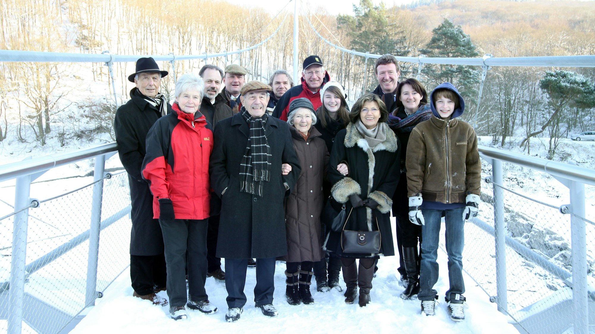 Eine Gruppe Menschen steht im Schnee auf einer Brücke.