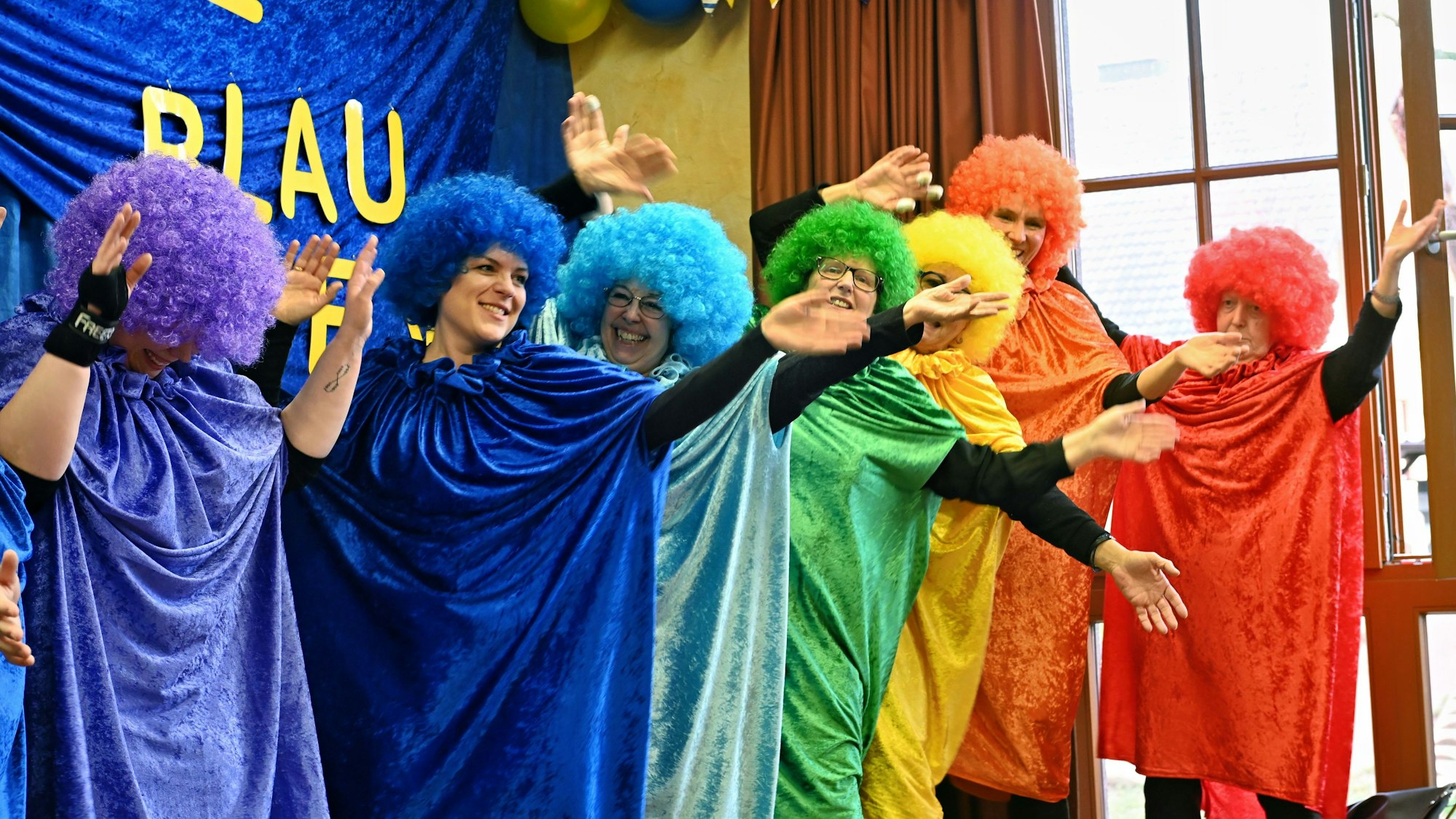 Das Bild zeigt eine Gruppe auf der Bühne. Sie ist so bunt verkleidet wie der Regenbogen.